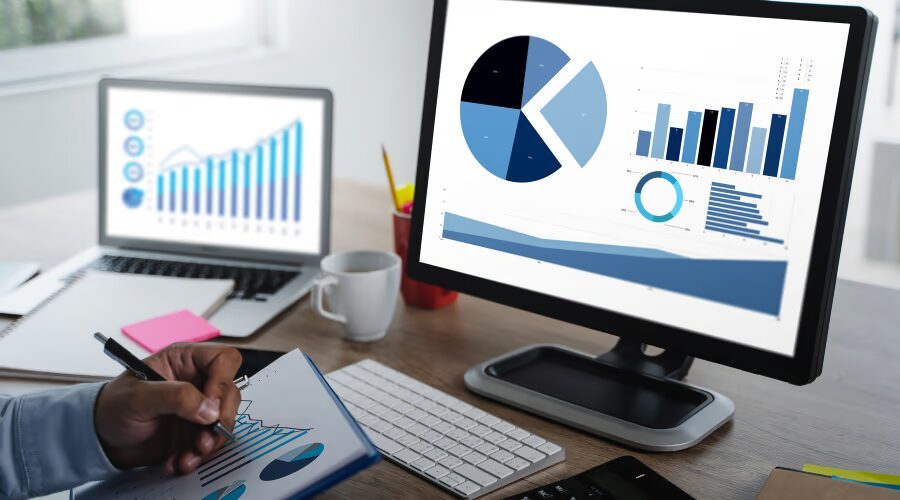 Profissional analisando gráficos e métricas de growth marketing em monitor e caderno de anotações